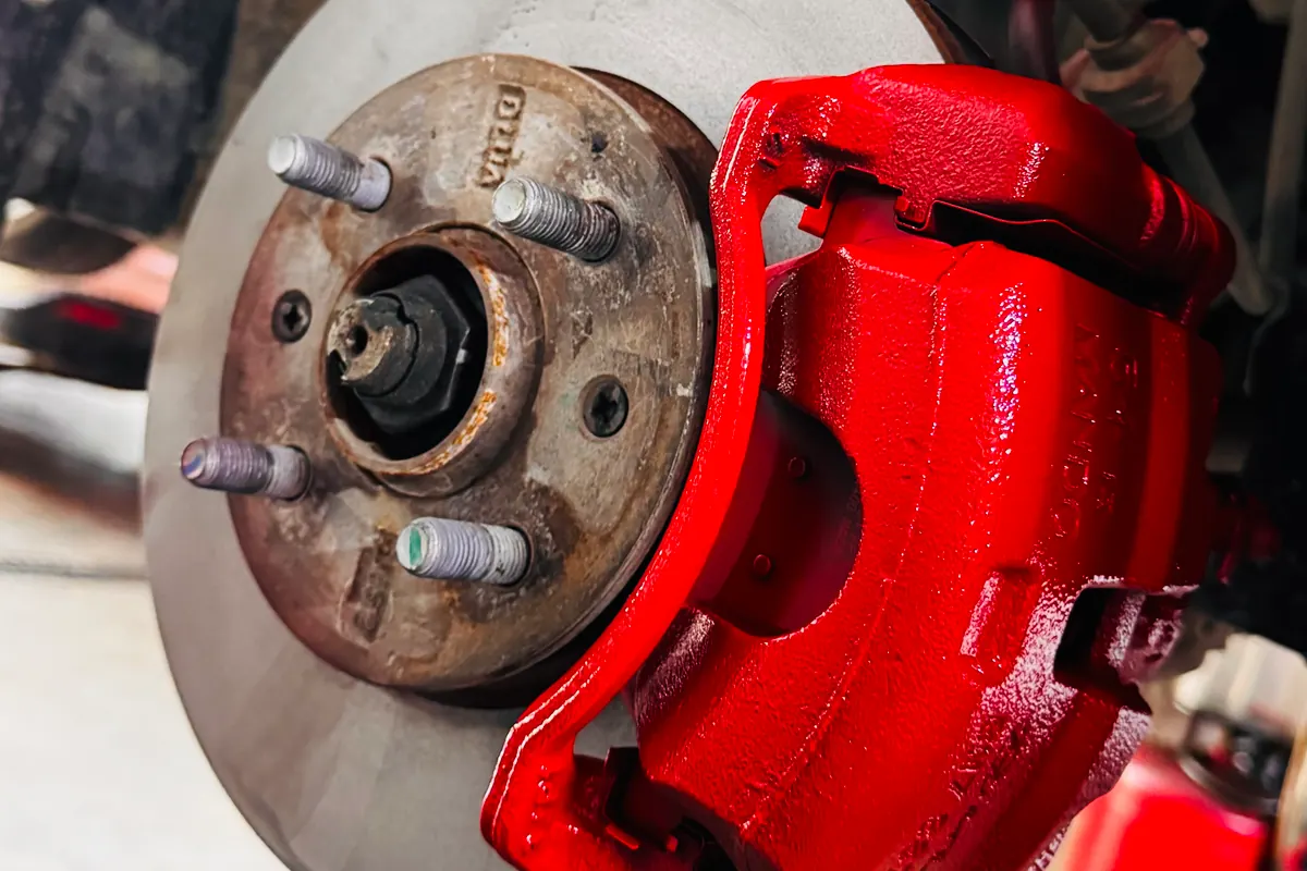 Disco de freno y caliper rojo de un vehículo en el taller